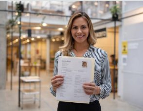 Junge Frau hält ihren Lebenslauf in einem modernen Arbeitsumfeld in den Händen.